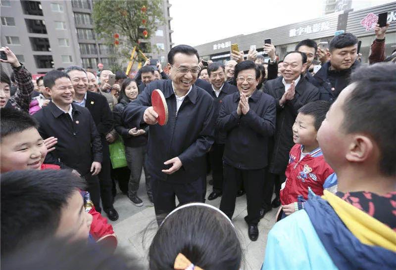 图为李克强在贵阳考察时，一群孩子围住总理“邀约”打乒乓球。